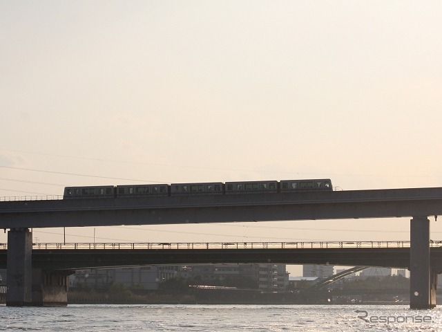 夕日を浴びながら隅田川を渡る日暮里・舎人ライナーの列車。