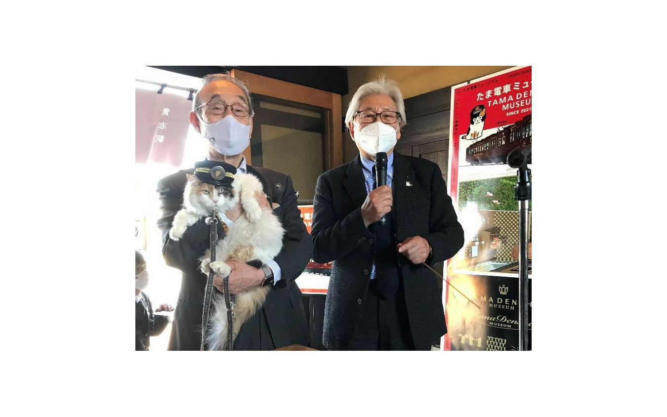 「ニタマ」こと二代目のたま駅長を抱く小嶋光信和歌山電鐵社長(左)。右はデザイナーの水戸岡鋭治氏。