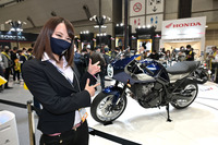 丸山浩氏とともにホンダブースを取材する小鳥遊レイラさん(ことりちゃん)。ホーク11とともに。