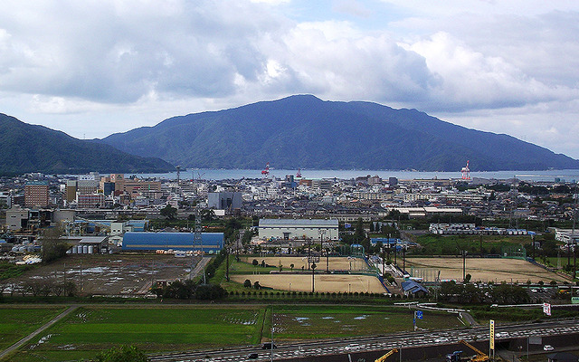 北陸道側から見た敦賀市街。手前の道路が国道8号（敦賀バイパス）、野球場がきらめきスタジアム。敦賀港の向こうに原発などが建つ敦賀半島が見える