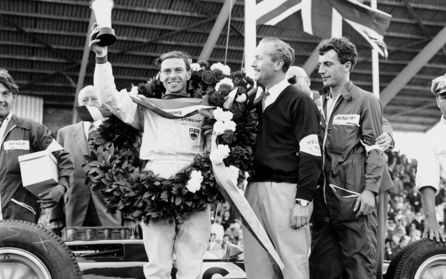 1963年イギリスGP、ジムクラークが25クライマックスで優勝。チャップマンとともに表彰台に上る