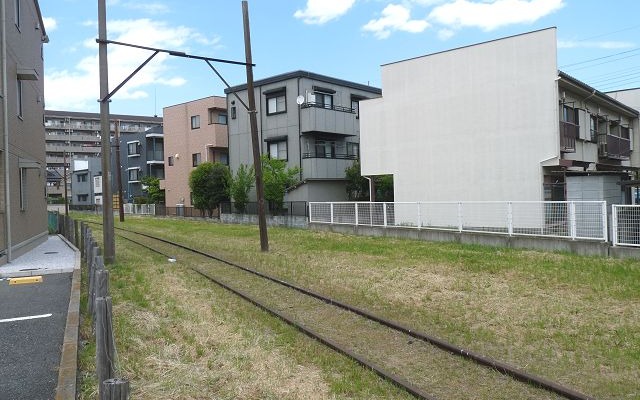 新宿線南大塚駅付近に残る赤さびたレールと木製の架線柱は、川砂利輸送を目的に建設された安比奈線の名残。法手続上は現在も休止であり、「廃線」ではない。