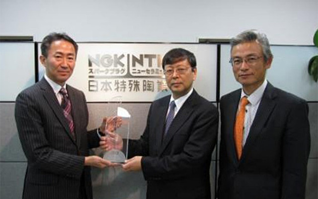 トムソン・ロイターの日本法人 代表取締役・冨井俊行氏（左）からトロフィーを授与するNGK大島崇文副社長（中央）および青木昇知的財産部長（右）