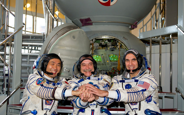 最終試験を終え、ソユーズ宇宙船シミュレータの前で手を握る若田光一、ミハイル・チューリン、リチャード・マストラキオ宇宙飛行士（左から）（出典：JAXA／GCTC）