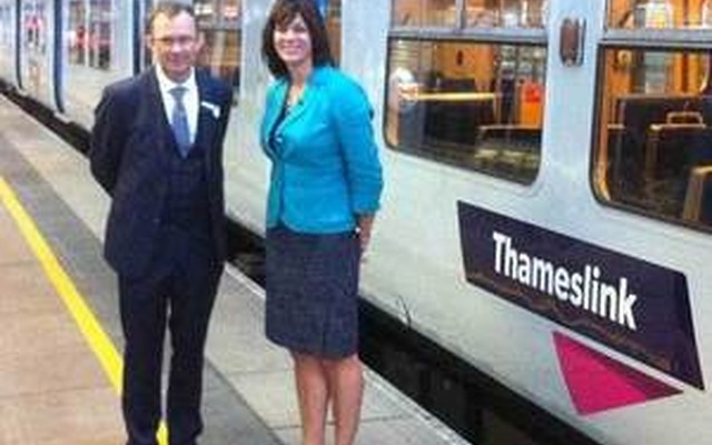 来夏には英国最大の列車運行会社となる予定の、ロンドン近郊の路線網を運行する「ゴヴィア・テムズリンク・レールウェイ」が運行を開始した。写真はロゴが入った列車と同社CEO（左）、ペリー鉄道相