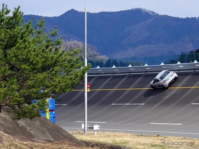 高速周回路バスツアーの横を220km/h超えで突っ走る、スバルドライビングアカデミートレーニング車(3月27日、栃木県佐野市・スバル研究実験センター)