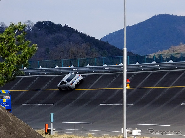 高速周回路バスツアーの横を220km/h超えで突っ走る、スバルドライビングアカデミートレーニング車(3月27日、栃木県佐野市・スバル研究実験センター)