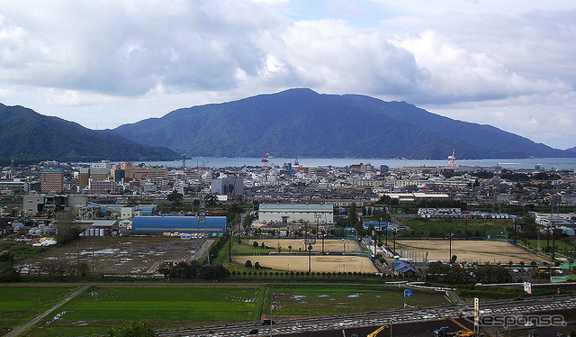 北陸道側から見た敦賀市街。手前の道路が国道8号(敦賀バイパス)、野球場がきらめきスタジアム。敦賀港の向こうに原発などが建つ敦賀半島が見える