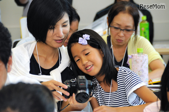 夏休みイベントの醍醐味は、親子で出来事を共有しながら学べること。子ども新聞に利用する写真を一緒に選定する親子のようす <撮影:稲葉九>