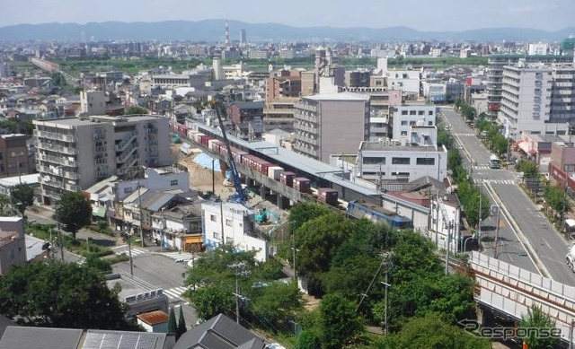 貨物列車が走り抜けて行く都島駅の工事現場。おおさか東線は貨物線を旅客化する形で整備が進められている。