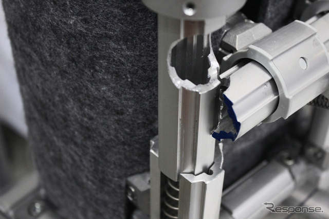 ロック機構のカットモデル。図は横方向のシャフトがロックされた状態で、縦シャフトが工具によって押し下げられると切り欠き同士が合致して、横シャフトが回転しロックが解除される仕組み。