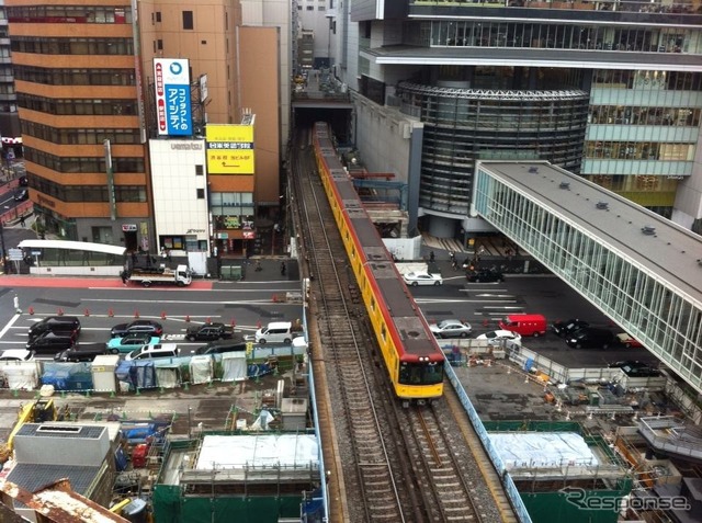 2012年3月、トンネルを出て渋谷駅に進入する電車。写真右上の建物がヒカリエで、線路との間に移設スペースがあるのがわかる。また新しい橋脚が従来の線路の両側に立ち上がっているのも見える。
