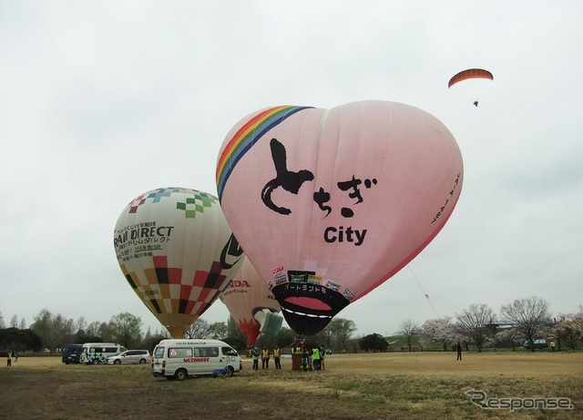 会場ではオフィシャルバルーンの繋留が行われていた。上空にはモーターパラグライダーが。