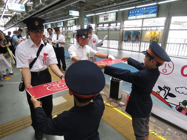 「こども駅長」が運転士と車掌に「OJICOトレイン」のヘッドマークを手渡した。