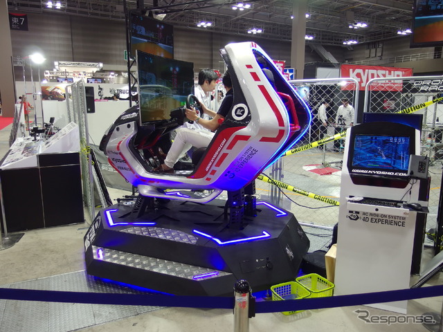 京商のKYOSHO RC RIDE-ON SYSTEM 4D EXPERIENCE(参考出品)。ドローン搭載カメラからの画像を前面ディスプレイに表示、座席の動きは機体と連動する(全日本模型ホビーショー2017)。