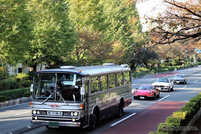 先頭を行くのは会場と国立駅を結ぶ無料シャトルバスの日野 RC700、そして参加者のディノ 246GT、メルセデス SL、MG B