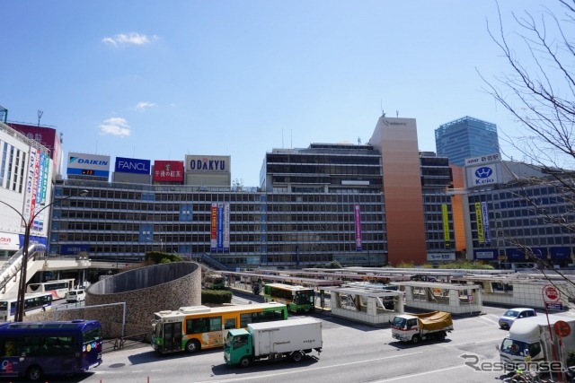 新宿駅西口地上バス乗り場。東西通路の予定地は、写真の右手、正面小田急デパートの右側、京王デパートの左側、オレンジ色の壁面のあたり。