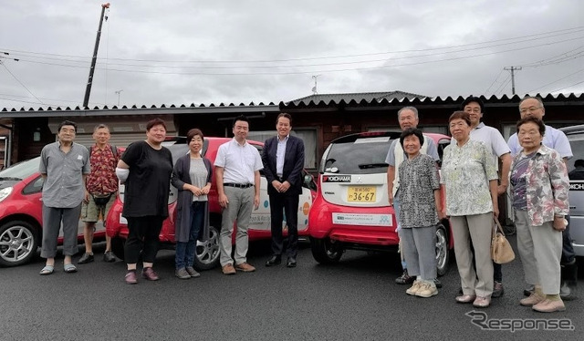 コミュニティ・カーシェアリングへのタイヤ寄贈セレモニーに参加した日本カーシェアリング協会の吉澤武彦代表理事（中央左）、横浜ゴムの森智朗CSR本部長代理（中央）とコミュニティ・カーシェアリングを利用する石巻市の人たち