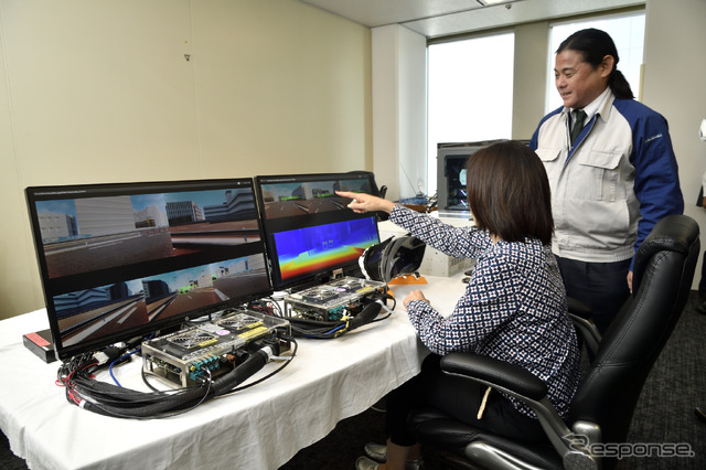 HILS+VR空間を実現する機材の説明を受ける飯田さん