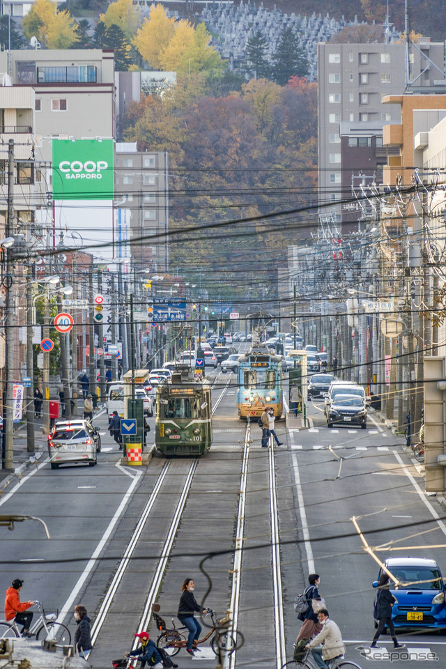 藻岩山をバックに西へ向かうM101号(左)。幌南小学校前~東屯田通。2021年10月31日。
