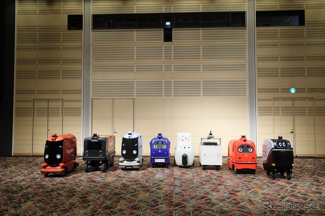 ロボットデリバリー協会各社の自動配送ロボット:向かって右から川崎重工業、ZMP、TIS、ティアフォー、日本郵便、パナソニック、本田技研工業、楽天グループ