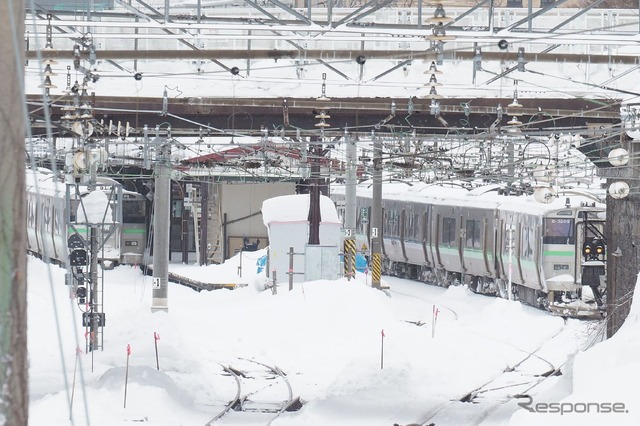 雪に埋もれるようにホームに佇む電車。2022年2月22日、函館本線小樽駅。