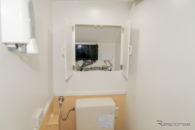 便器の奥には扉があり、センサーなどのコントロール部分が設置されていた。左上に見えているのは、便座用の除菌剤の入ったポンプ。