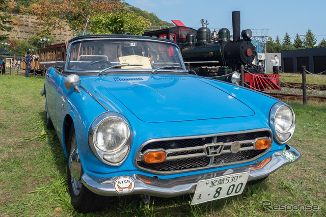 ホンダのオープンカー『S800』(1966年モデルのAS800)の脇を通る蒸気機関車『アイアンホース号』。