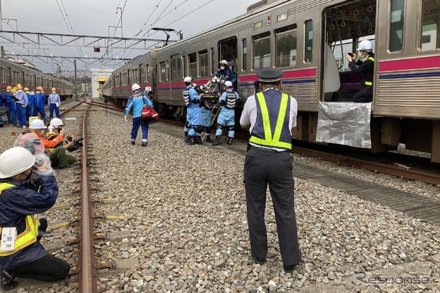 京王電鉄・総合事故復旧訓練:重傷者の搬送。写真中央、背中の人物はバディコムを使用中だ。