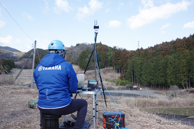 写真中央右の小さな点が、自動航行中の無人ヘリ。常にパイロットがモニターする。