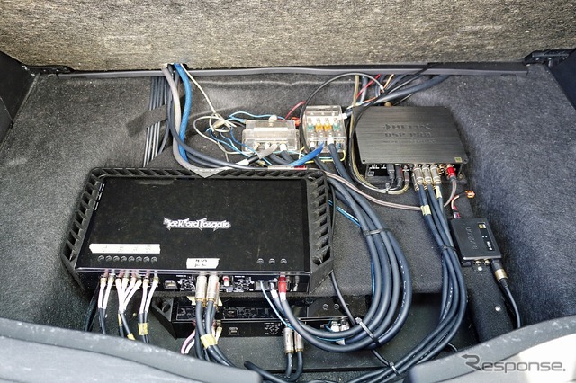 フロアボードを2枚重ねした3層構造のラゲッジの奥底にはパワーアンプやDSPなどが整然とレイアウトされている。