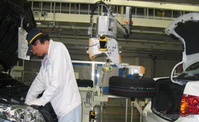 自動車の組立工場においてスペアタイヤを自動車のトランクに搭載するロボット