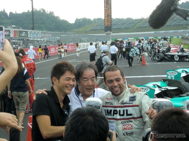 勝ったオリベイラ(右)と祝福する星野一義監督(中央)。星野監督に呼ばれて、かつての自軍エース・本山哲(左)も飛び入りで肩を組む