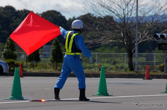 後続車に事故発生を知らせる旗振りは重要な作業。
