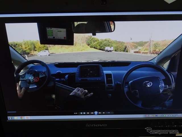 運転のデモ映像。運転者がリモコン代わりに操作しているのは、助手席に設置したゲーム機用のハンドル型コントローラー。