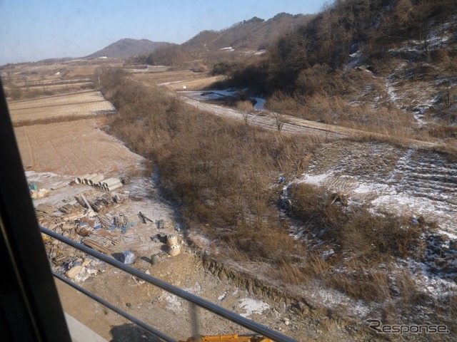 新炭里(シンタンリ)駅から先が今回の営業再開区間。しばらくは旧線をトレースするように進むが、ルートの一部が変更されたため途中から旧線と分かれる。写真の右下から左上に延びる枯れ草が旧線の築堤。