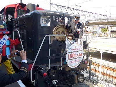 嵯峨野トロッコ列車の年間利用者数が3月19日、初めて100万人を突破した。写真は記念のヘッドマークを取り付ける乗客代表ら