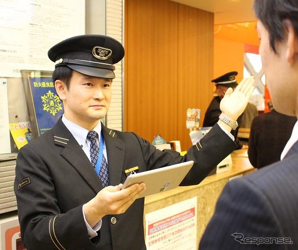 携帯端末で運行状況を確認・案内する駅員のイメージ。3月31日から18駅で実施する。