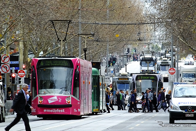 イチゴ色のD-class電車がSwanston St を走る。この電車の行き先はメルボルン大学（Route 6）。Melbourne Festival（2014/10）の広告が車体に付く。