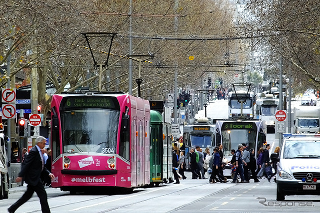 イチゴ色のD-class電車がSwanston St を走る。この電車の行き先はメルボルン大学(Route 6)。Melbourne Festival(2014/10)の広告が車体に付く。