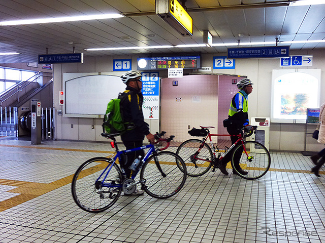 自転車を転がして千葉みなと駅の改札口を通る参加者たち(11月30日、千葉モノレール実証実験「サイクル&モノレール」)
