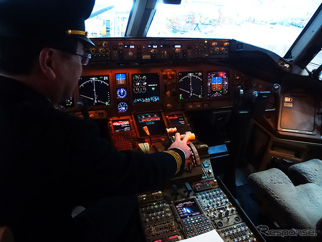 B777(JA8979)のコックピット。船越機長がスラスト・レバーに手をおく(羽田空港内JALメインテナンスセンター1(M1ハンガー))