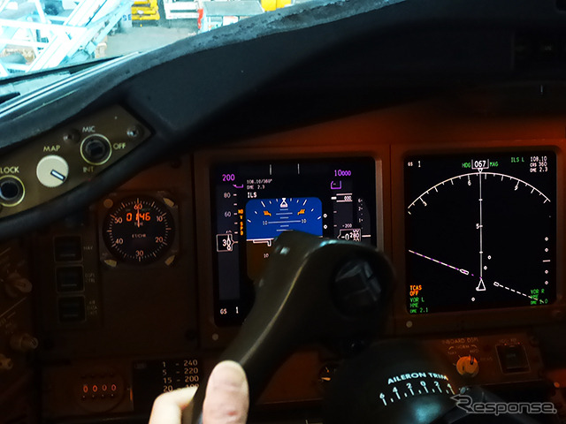 操縦ホイールをまわす船越機長。「手動で操縦ホイールやラダーペダルを操作し、まっすぐに飛ぶ状態にしたあとにトリムスイッチを操作して手を放してもまっすぐに飛ぶように調整します」(日本航空) 羽田空港内JALメインテナンスセンター1(M1ハンガー)