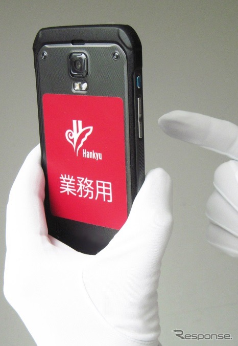 車掌が携行するスマホ型端末のイメージ。「業務用」であることを明示するシールが貼られている。