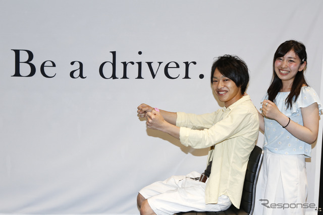 会場に用意された「Be a driver」コーナーで記念撮影する20代カップルの参加者