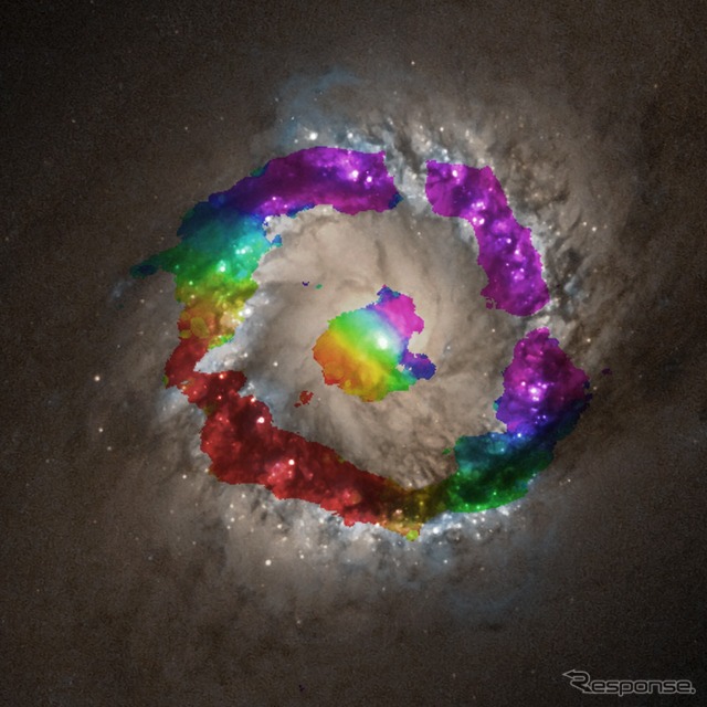 アルマ望遠鏡で観測したNGC 1097中心部。アルマ望遠望遠鏡で観測したHCN（シアン化水素）ガスの運動を色で表し、ハッブル宇宙望遠鏡で撮影された可視光画像の上に合成