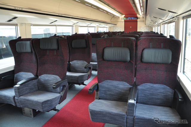 E353系グリーン車の室内。落ち着いた色彩のシートに床と天井の赤が印象的だ