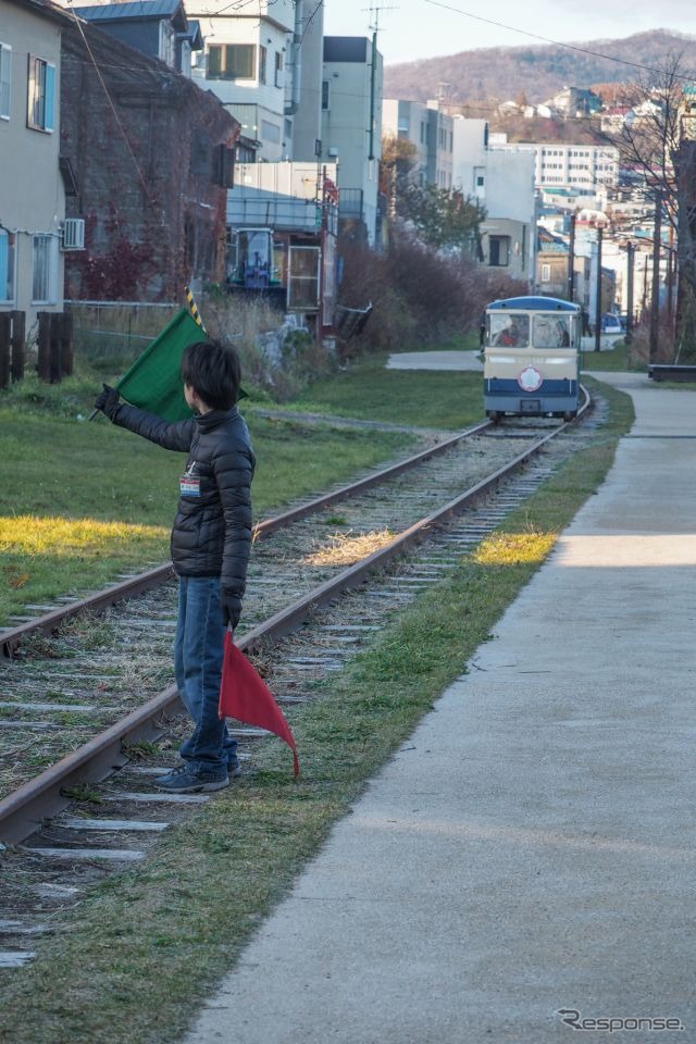 トロッコが接近するとスタッフが安全のために旗を振る。鉄道車両の入換えを思い出す光景だ。