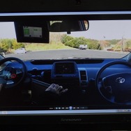 運転のデモ映像。運転者がリモコン代わりに操作しているのは、助手席に設置したゲーム機用のハンドル型コントローラー。