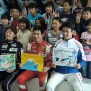 見学に訪れた小学生たちと日本人ドライバーの記念撮影。前列右から中嶋一貴、小林可夢偉、井原慶子。